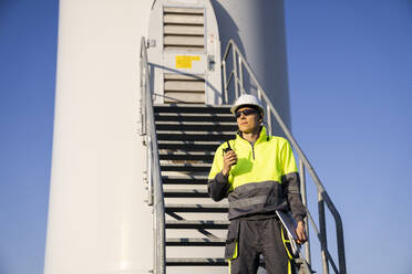 Ingenieur steht vor der Treppe einer Windkraftanlage - EKGF00512