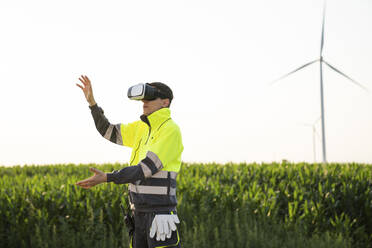 Ingenieur trägt VR-Simulator und gestikuliert im Feld - EKGF00546