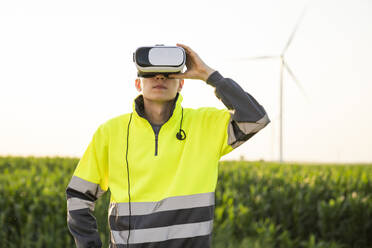 Ingenieur mit VR-Simulator steht an einem sonnigen Tag auf einem Feld - EKGF00548