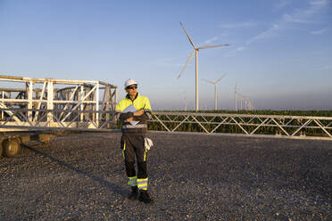 Engineer in reflective clothing and hardhat standing on road - EKGF00573