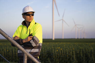 Engineer with arms crossed in front of wind turbine farm - EKGF00583