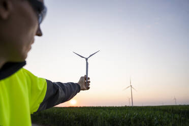 Engineer with model of wind turbine at sunset - EKGF00592