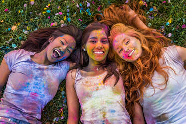 Group of happy friends playing with holi colors in a park - Young adults having fun at a holi festival, concepts about fun, fun and young generation - DMDF04384