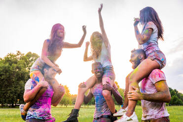 Group of happy friends playing with holi colors in a park - Young adults having fun at a holi festival, concepts about fun, fun and young generation - DMDF04386