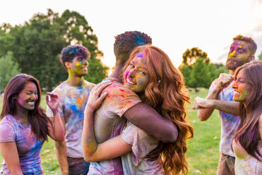 Group of happy friends playing with holi colors in a park - Young adults having fun at a holi festival, concepts about fun, fun and young generation - DMDF04387