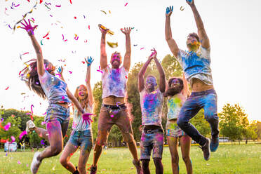 Group of happy friends playing with holi colors in a park - Young adults having fun at a holi festival, concepts about fun, fun and young generation - DMDF04391