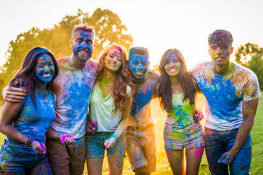 Group of happy friends playing with holi colors in a park - Young adults having fun at a holi festival, concepts about fun, fun and young generation - DMDF04392