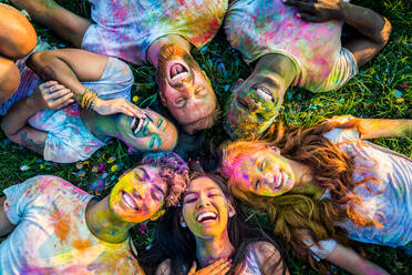 Group of happy friends playing with holi colors in a park - Young adults having fun at a holi festival, concepts about fun, fun and young generation - DMDF04393