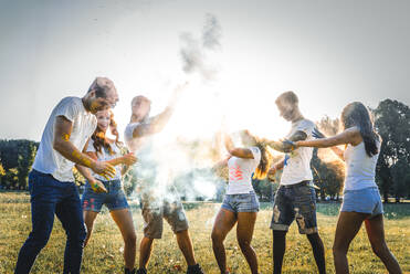 Group of happy friends playing with holi colors in a park - Young adults having fun at a holi festival, concepts about fun, fun and young generation - DMDF04398