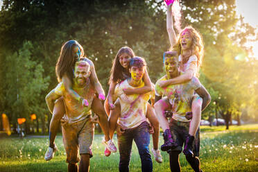 Group of happy friends playing with holi colors in a park - Young adults having fun at a holi festival, concepts about fun, fun and young generation - DMDF04402