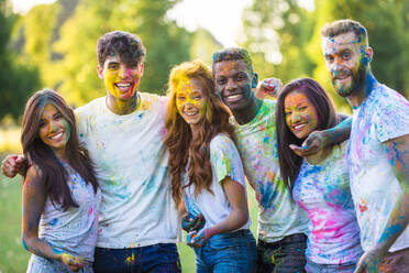 Group of happy friends playing with holi colors in a park - Young adults having fun at a holi festival, concepts about fun, fun and young generation - DMDF04403