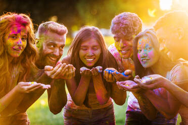 Group of happy friends playing with holi colors in a park - Young adults having fun at a holi festival, concepts about fun, fun and young generation - DMDF04418