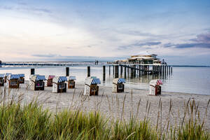 Deutschland, Schleswig-Holstein, Timmendorfer Strand, Strandkörbe mit Kapuze mit Seebrücke und Mikado Teehaus im Hintergrund - EGBF00920