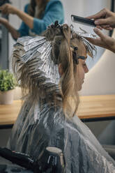 Hairdresser combing client's hair at salon - EVKF00042