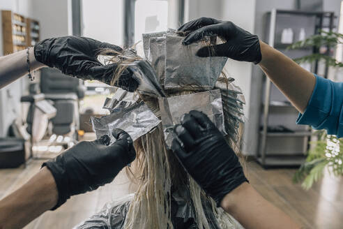 Friseure beim Färben der Haare eines Kunden im Salon - EVKF00045