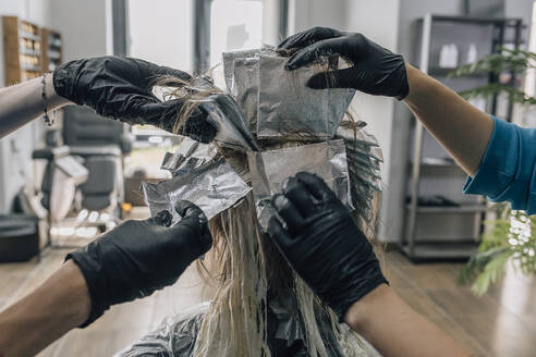 Hairdressers dyeing customer's hair in salon - EVKF00045