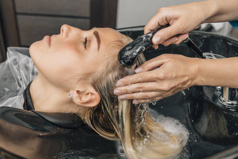 Friseurin wäscht die Haare einer Kundin im Salon - EVKF00046