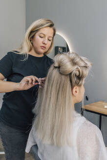 Friseurin kämmt das Haar eines Kunden im Salon - EVKF00048