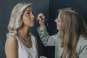 Kosmetikerin trägt Augen-Make-up auf eine Kundin im Salon auf - EVKF00050
