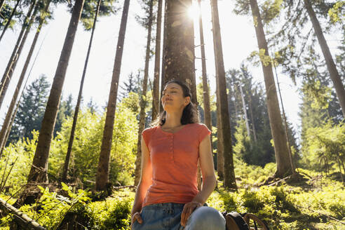 Woman with eyes closed in forest on sunny day - DIGF20527