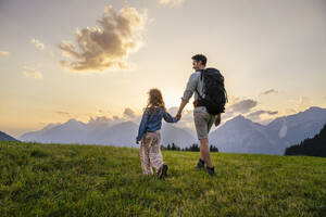 Father exploring with daughter in meadow at sunset - DIGF20536