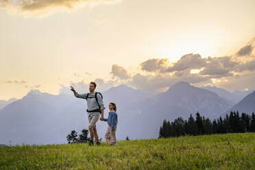 Father pointing and walking with daughter in meadow - DIGF20538