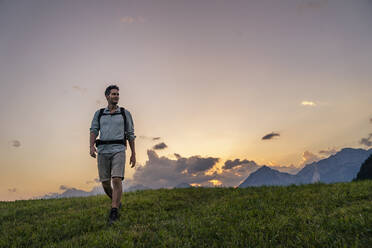 Man hiking in meadow at sunset - DIGF20558
