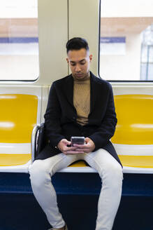 Young man using smart phone in train - JPTF01313