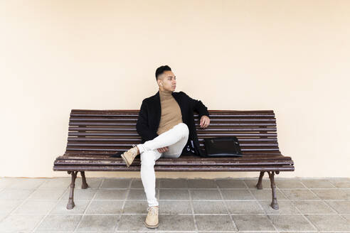 Contemplative man sitting on bench at railroad station - JPTF01316