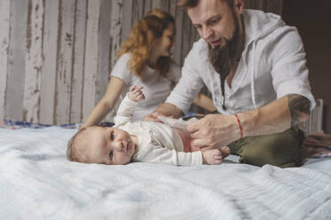 Vater wechselt die Windel seiner neugeborenen Tochter im Bett zu Hause - IHF01669