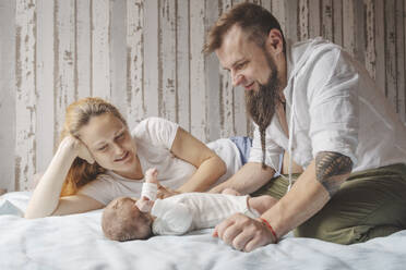 Eltern spielen mit neugeborener Tochter im Bett zu Hause - IHF01672