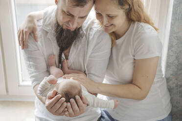 Happy parents carrying newborn daughter at home - IHF01676