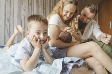 Boy with mother breastfeeding newborn daughter on bed at home - IHF01681