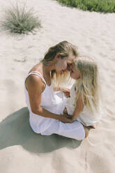 Glückliche Mutter umarmt Tochter am Strand an einem sonnigen Tag - SIF00824