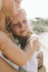 Mother hugging daughter at beach - SIF00826