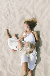 Mutter und Tochter entspannen sich im Sand am Strand - SIF00845