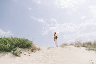 Mother carrying daughter at beach under sky - SIF00853