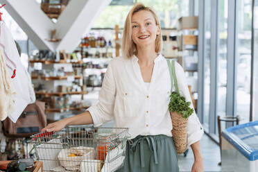 Glückliche Frau beim Einkaufen von Lebensmitteln im Geschäft - NDEF01079