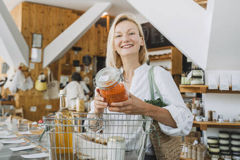 Glückliche Frau beim Einkaufen von roten Linsen im Geschäft - NDEF01080