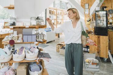 Blonde Frau mit Einkaufskorb in einem Geschäft - NDEF01088