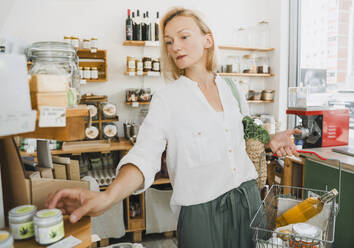 Blonde Frau kauft Hautpflegeprodukte in einem Geschäft - NDEF01093