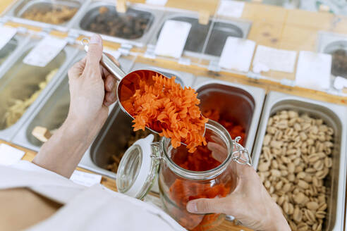 Hands of woman filling pasta in glass jar - NDEF01116