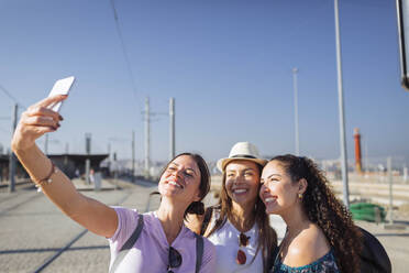 Happy woman taking selfie with friends through smart phone on sunny day - DCRF01833