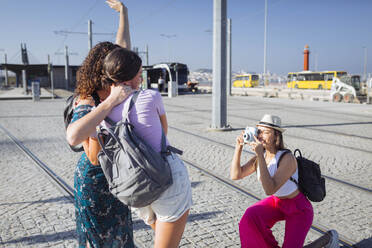 Frau mit Hut fotografiert Freunde mit Kamera auf Straßenbahngleisen - DCRF01839