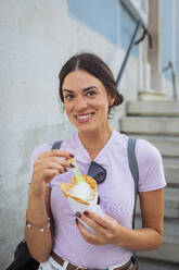 Happy woman standing with ice cream cone - DCRF01852