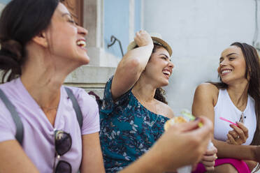 Cheerful friends laughing and having ice cream in front of building - DCRF01859