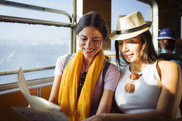 Smiling friends reading map in train - DCRF01878