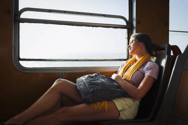 Junge Frau mit Rucksack entspannt im Zug - DCRF01880