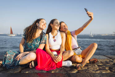 Happy woman taking selfie with friends at promenade - DCRF01893