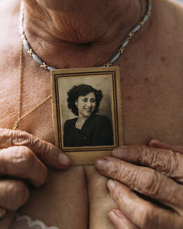 Ältere Frau hält Bild aus der Vergangenheit auf der Brust - EGHF00775
